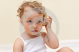 Little girl listens to the sound of a seashell.