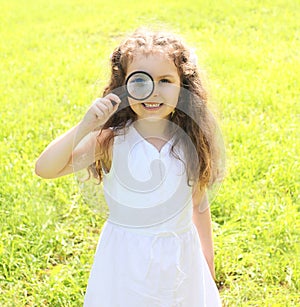 Little girl child looking through a magnifying glass on nature