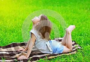 Little girl child lying on the grass does yoga exercise