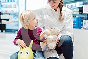 Little girl child in the pharmacy talking to the chemist