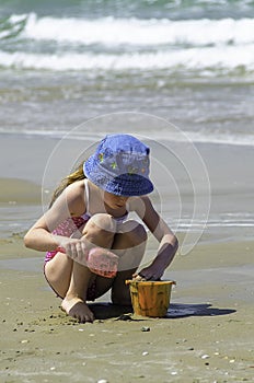 Little girl child playing with the sand in the sea