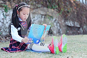 Little girl Child reading a book on the grass