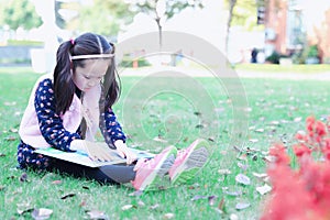 Little girl Child reading a book on the grass