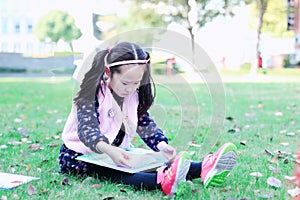 Little girl Child reading a book on the grass