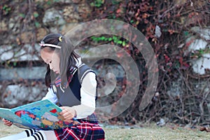 Little girl Child reading a book on the grass