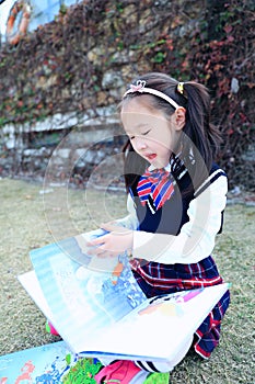 Little girl Child reading a book on the grass