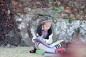 Little girl Child reading a book on the grass