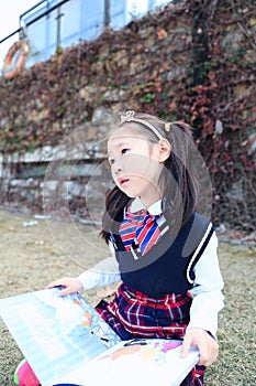 Little girl Child reading a book on the grass