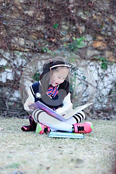 Little girl Child reading a book on the grass