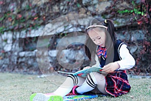 Little girl Child reading a book on the grass