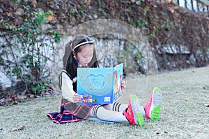Little girl Child reading a book on the grass