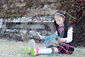 Little girl Child reading a book on the grass