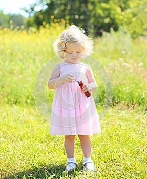 Little girl child with soap bubbles in sunny summer