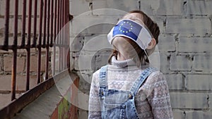 Little girl child wearing a protective medical mask with a flag of Europe, the European Union