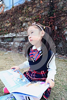 Little cute girl Child reading a book on the grass