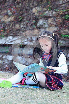 Little girl Child reading a book on the grass