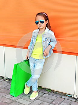 Little girl child wearing a sunglasses and jeans clothes with shopping bags