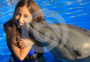 Little girl children kissing a gorgeous dolphin flipper smiling face happy kid swim bottle nose dolphins