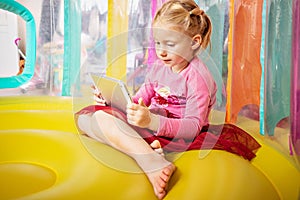 A little girl in the children`s room at home looks at lessons on the tablet. Distance learning in the coronavirus pandemic