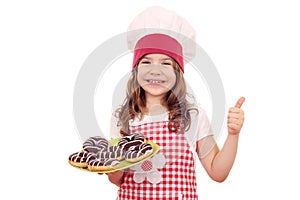 Little girl with chocolate donuts and thumb up