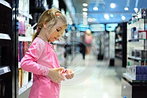 Little girl choose perfume in perfume shop