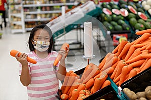 Little girl choosing carrot in a food store