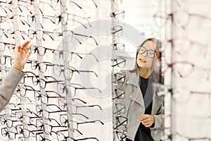 Little girl taking eyeglasses from shelves in optica photo