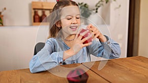 Little girl choosing fresh red apple against sweet cake