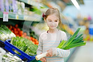 Little girl choosing a leek in a food store