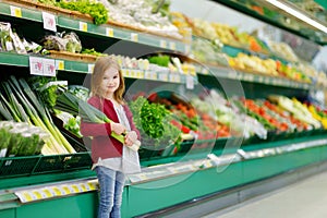 Little girl choosing a leek in a store