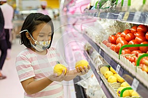 Little girl choosing lemon in a food store