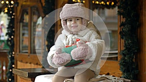 Little girl at the Christmas market. The child is holding a box with a present in her hand.