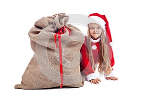 Little girl in christmas outfit hiding behind santa bag