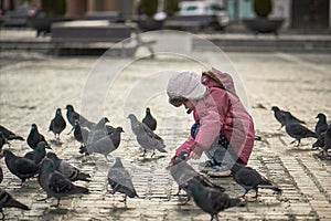 Little girl in a city square feeding pigeons