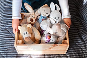 Little girl cleaning up the toy box at home.