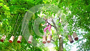 Little girl climbing in adventure activity park with helmet and safety equipment. Climber little girl on training. Cute
