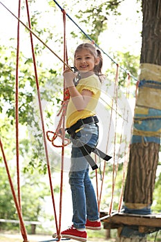 Little girl climbing in adventure park.