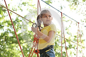 Little girl climbing in adventure park. Summer