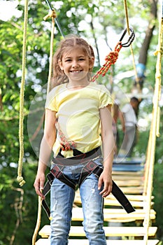 Little girl climbing in adventure park. Summer