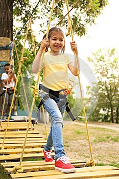 Little girl climbing in adventure park. Summer