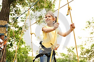 Little girl climbing in adventure park. Summer