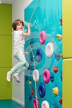 Little girl is climbing in child sport park on wall