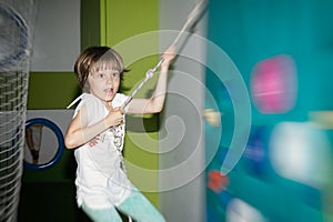 Little girl is climbing in child sport park on wall