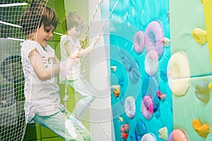 Little girl is climbing in child sport park on wall