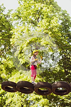 Little girl climbing on high rope park. Little girl climbing in adventure activity park with helmet and safety equipment