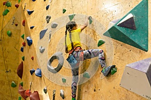 little girl climbing a rock wall indoor