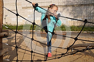 Little girl climbing rope ladder on the playground
