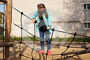 Little girl climbing rope ladder on the playground