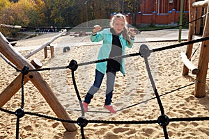 Little girl climbing rope ladder on the playground