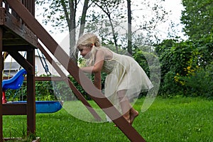 Little girl climbing swingset ladder in a dress